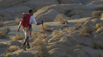um jovem mochilando em um deserto montanhoso.
