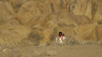 un giovane zaino in spalla in un deserto montuoso. video
