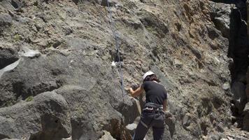 una mujer asegurando a un hombre mientras escalaba en roca.