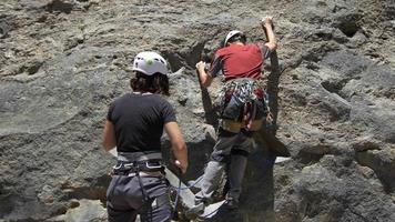 una mujer asegurando a un hombre mientras escalaba en roca.