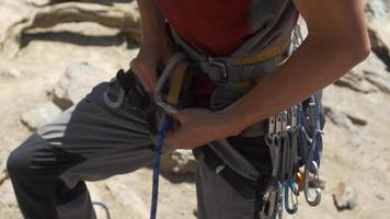 A young man using a figure eight follow-through knot to tie his rope to his harness while rock climbing.