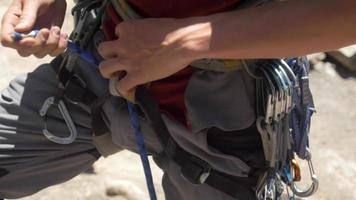 A young man using a figure eight follow-through knot to tie his rope to his harness while rock climbing.