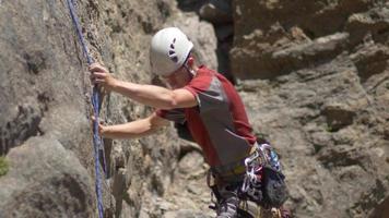 un joven tirando de su cuerda hacia abajo después de escalar en roca.
