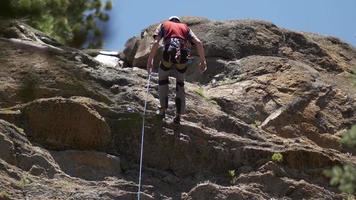 en ung man som stöter ner ett berg medan han klättrar. video