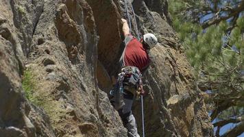 en ung man som klättrar på ett berg. video