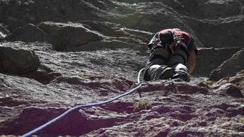 een jonge man rotsklimmen op een berg.