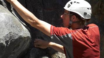 Detalle de un joven escalada en roca y agarrándose. video