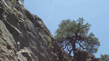 A woman belaying a man while rock climbing.