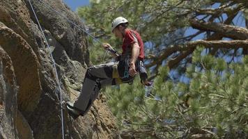 een jonge man die een berg afstoot tijdens rotsklimmen. video