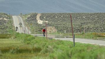 um homem andando de bicicleta em uma estrada panorâmica.