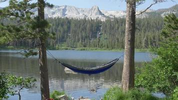 An empty hammock near a mountain lake. video