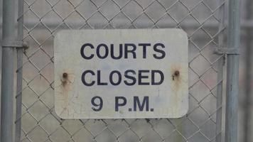 Segno di ore del campo da basket sulla recinzione di collegamento a catena che circonda il campo all'aperto