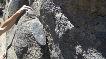 Detalle de un joven escalada en roca y agarrándose. video