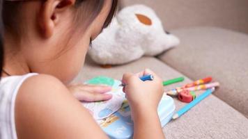 lindo y pequeño niño en edad preescolar dibujando y coloreando en casa, quédese en casa durante el brote de coronavirus. concepto de educación en el hogar. video