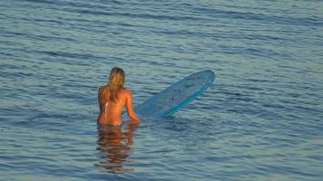 uma jovem surfando de biquíni em uma prancha de surfe longboard.