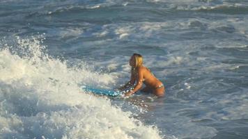 una giovane donna che naviga in bikini su una tavola da surf longboard.