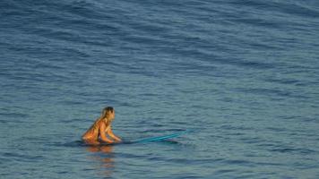 een jonge vrouw surfen in een bikini op een longboard surfplank.