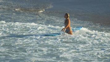una giovane donna che naviga in bikini su una tavola da surf longboard.