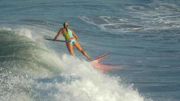 een jonge vrouw sup surfen in een bikini op een stand-up paddleboard surfplank. video