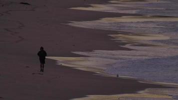 A man jogging on the beach at dawn.