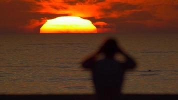 silhouette d'un homme regardant le coucher de soleil sur la plage. video