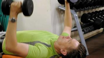 Man doing bench press with dumbbells in fitness studio video