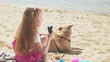 menina toma sorvete e dá comida ao cachorro ao ar livre