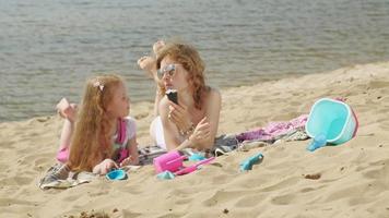 Mom and daughter on the river bank eat ice cream Outdoor recreation video