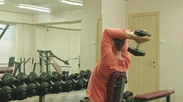 Hombre haciendo press de banca con pesas en fitness studio video