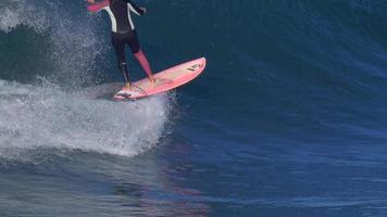 Eine Frau fährt auf einem SUP-Stand-Up-Paddleboard, während sie auf einem rosa Surfbrett surft. video