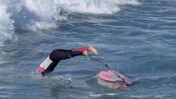 en kvinna rider en sup stand up paddleboard medan du surfar på en rosa surfbräda. video