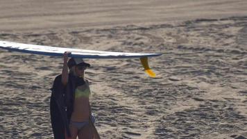 uma jovem caminhando com sua prancha de surf longboard. video