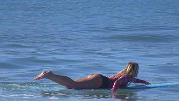 una giovane donna che rema su una tavola da surf longboard. video