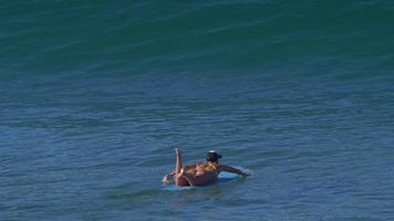 uma jovem de biquíni remando em uma prancha de surfe longboard. video