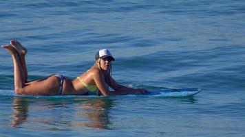 uma jovem de biquíni remando em uma prancha de surfe longboard. video