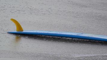 een blauwe longboard surfplank op het strand.