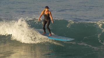 une jeune femme en combinaison de surf sur une planche de surf longboard. video