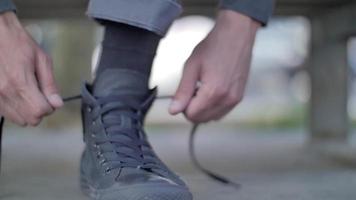um jovem amarra seus sapatos de cano alto antes de andar de skate.