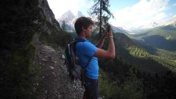un hombre tomando una foto con un dispositivo móvil en las montañas.