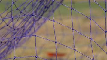 Details eines Netzes und eines Tors bei einem Fußballspiel.