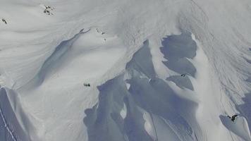 Luftaufnahme von Skifahrern, die vom Gipfel eines Berges Skifahren.