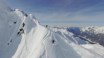 Luftaufnahme von Skifahrern, die vom Gipfel eines Berges Skifahren.