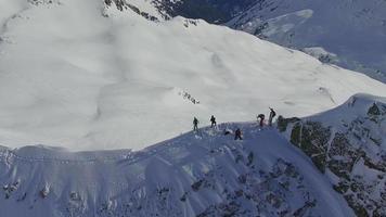 ripresa aerea di sciatori che sciano dalla cima di una montagna. video