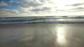 spårningsskott av havets vågor, stranden och piren vid solnedgången. video