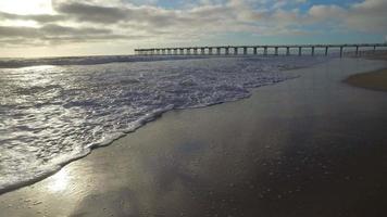 foto de rastreamento das ondas do mar, praia e cais ao pôr do sol. video