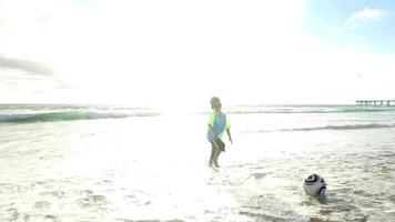 un niño hace una mueca en la playa al atardecer. video