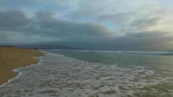 spårningsskott av havets vågor, stranden och piren vid solnedgången. video