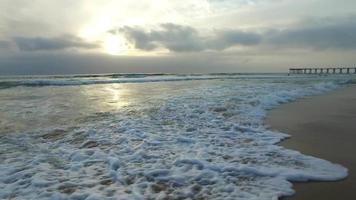 foto de rastreamento das ondas do mar, praia e cais ao pôr do sol. video