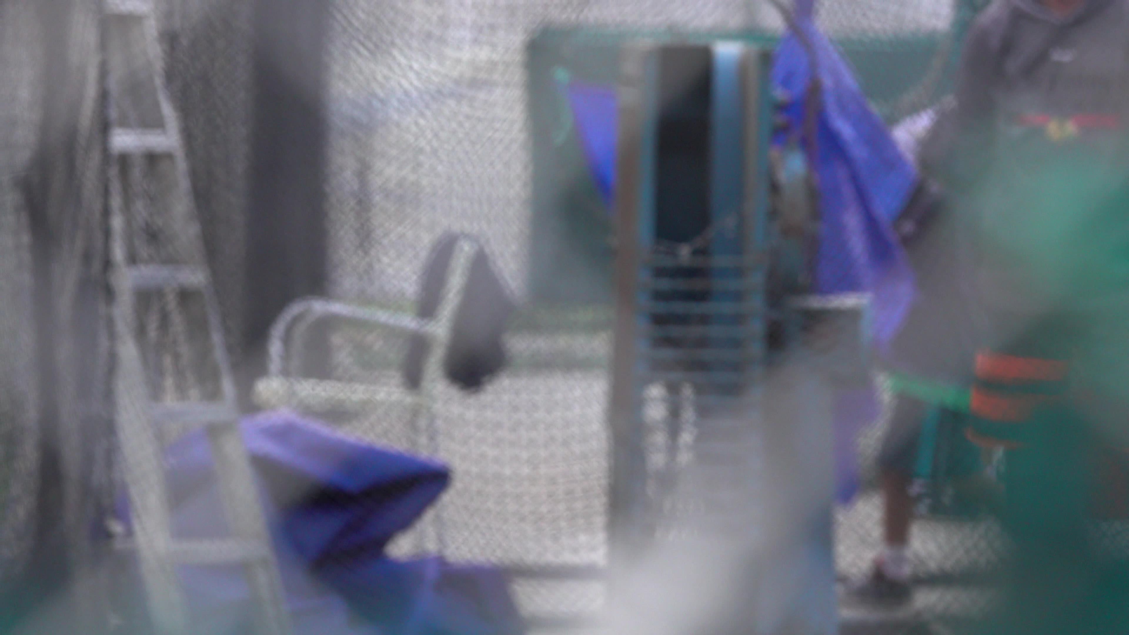 A vintage pitching machine throws a yellow baseball towards a batter