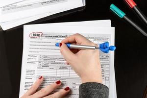 Woman fills the tax form, working with tax documents. Form 1040 Individual Income Tax return form. United States Tax forms. American blank tax forms. Tax time.